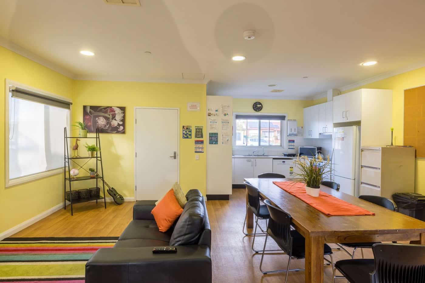 Common living-room-with-view-of-kitche_-side-shelf-and-electric-guitar-for-entertaining-guests