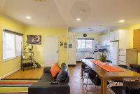Common living-room-with-view-of-kitche_-side-shelf-and-electric-guitar-for-entertaining-guests